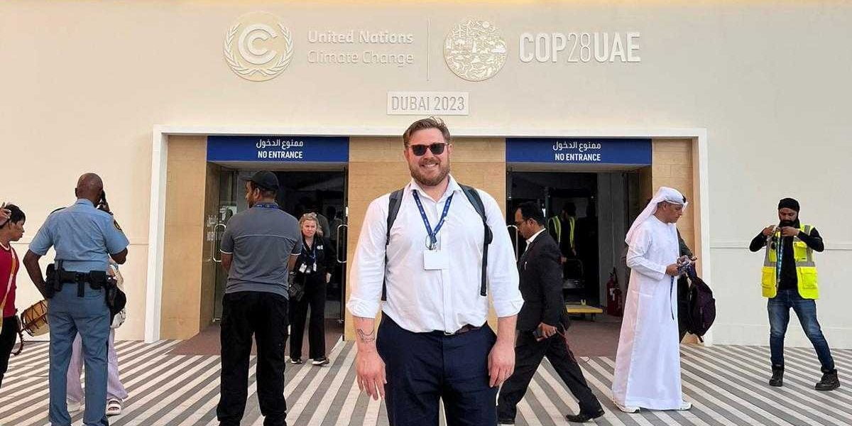 A photo of Pat Hinton at the entrance to COP28.